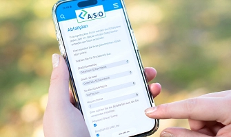 Hämde halten ein Smartphone. Auf dem Smartphone ist die Webseite der ASO zu sehen. Überschrift der Webseite ist "Abfallplan".