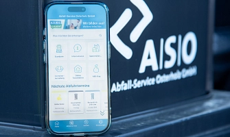 Foto eines Telefons, auf dem die neue ASO-App geöffnet ist, das auf einer Mülltonne neben dem ASO-Logo steht.
